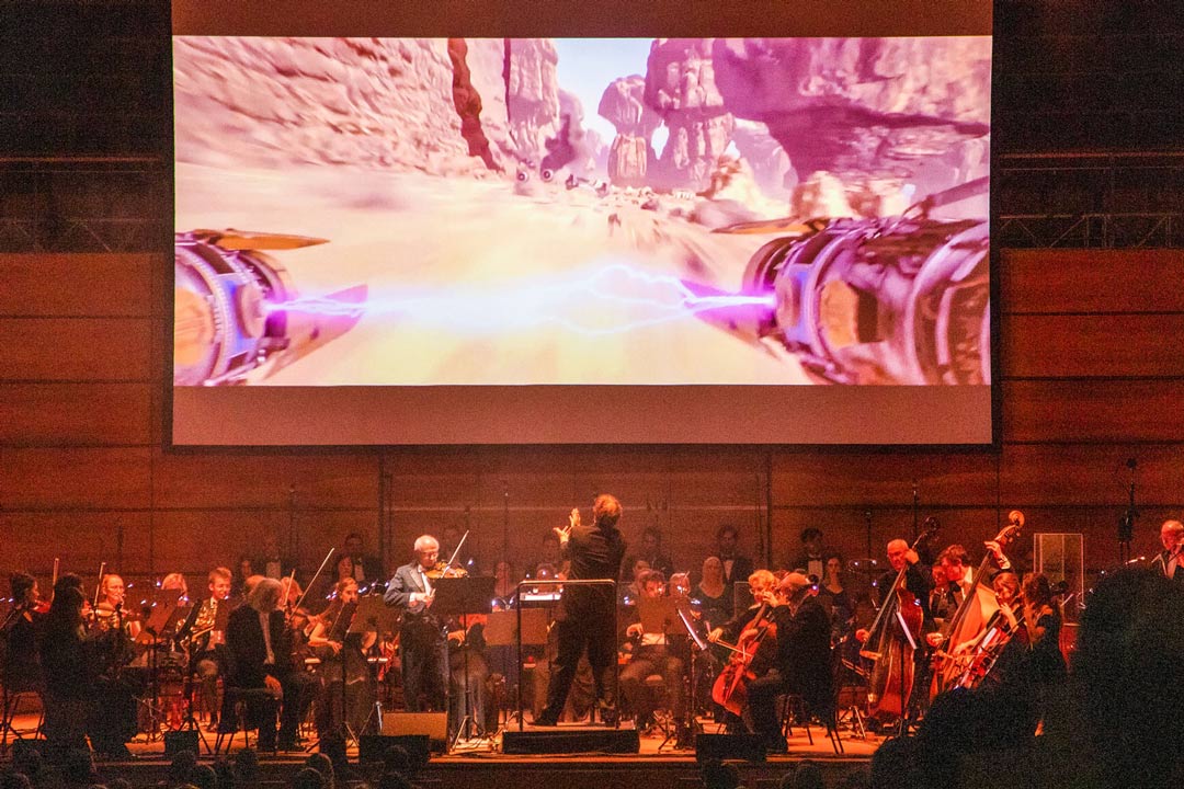 Orchester auf der Bühne mit Leinwand im Hintergrund, Fotocredit Highlight-Concerts